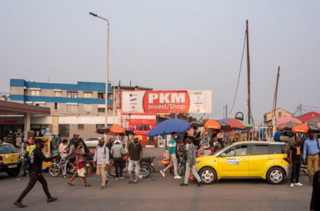 Bystanders gather at Kintambo Magasin currency market in Kinshasa on August 11, 2021. – How to make the Congolese franc a strong enough currency to regain its rights against the omnipotent US dollar.  The « de-dollarisation » of the economy, a sea serpent of Congolese financial policy, has just been put back on the drawing board in Kinshasa. The US dollar made its home in the former Zaire during the four-figure hyperinflation of the Mobutu years, as it did in other countries in the grip of chaos in Africa and elsewhere. (Photo by Arsene MPIANA / AFP)