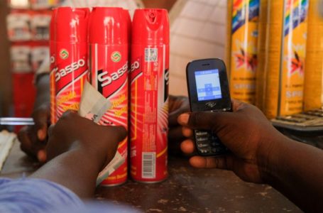 A customer holds his mobile phone as he prepares to pay for mosquito sprays at Makola market, one of the country’s largest trading centres in Accra, Ghana March 26, 2022. Picture taken March 26, 2022. REUTERS/Francis Kokoroko